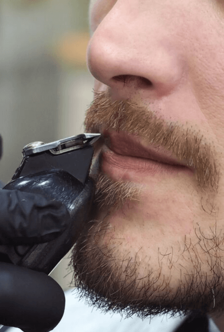 Man trimming moustache with electric shaver
